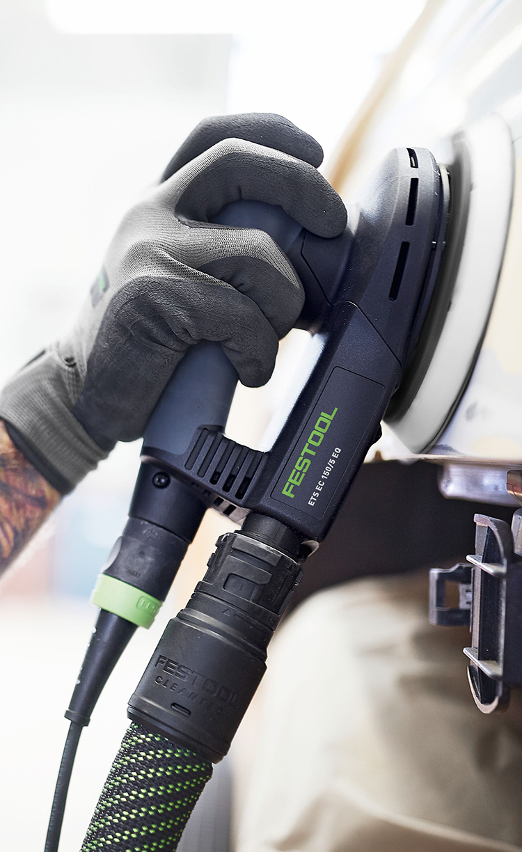 Mann mit Atemschutz schleift eine lackierte Oberfläche