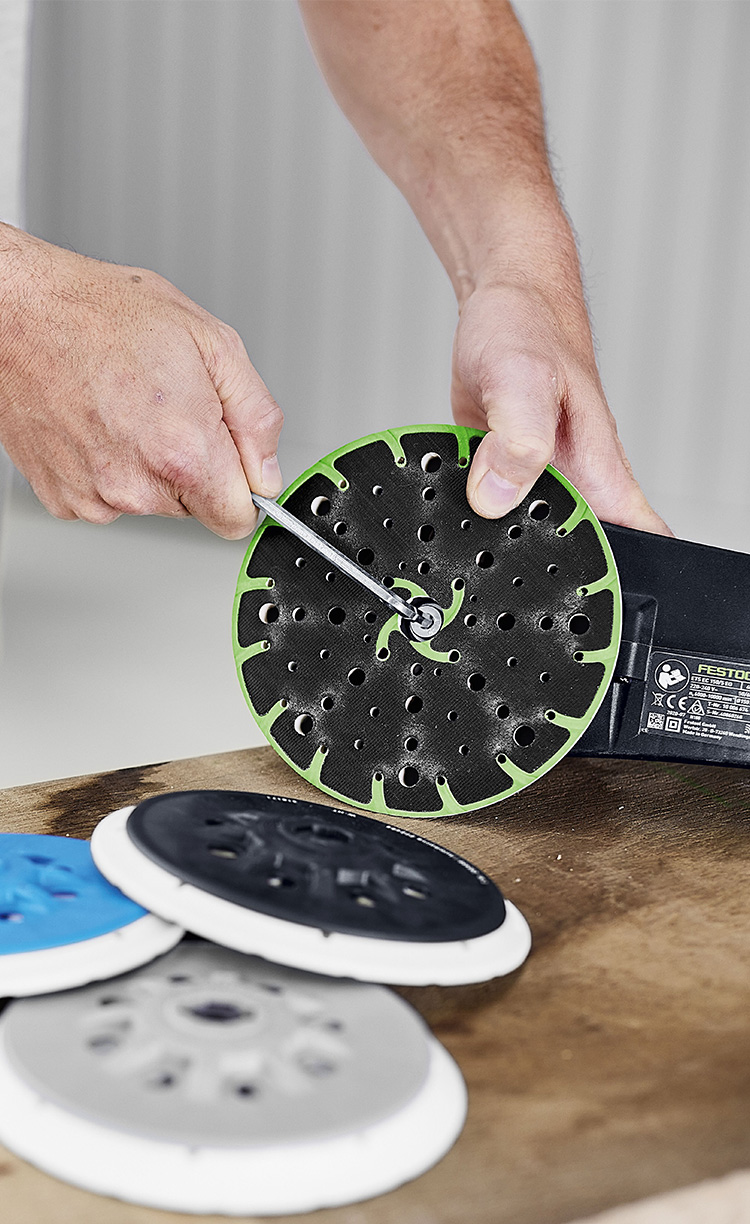 Ein Mann befestigt einen Schleifteller mithilfe eines Schraubenziehers