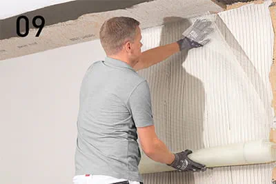 Armierungsgewebe mit dem Glätter in senkrechten Bahnen faltenfrei und überlappend in den Armierungsmörtel einarbeiten.