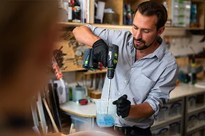 Richard uses a cordless drill to stir the resin he is using for his art