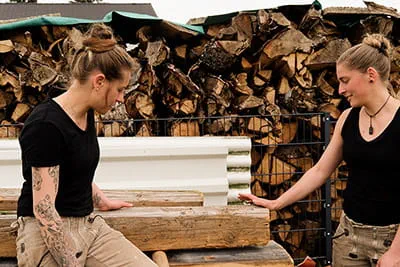 Zwei Schreinerinnen begutachten das Holz für das nächste Projekt
