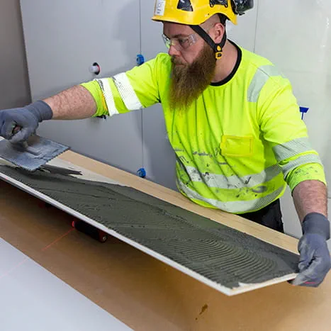 Vorbereitende Arbeit beim Fliesenlegen: Auftrag von Kleber mit dem Spachtel