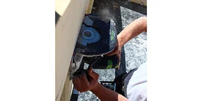 Die Akku- Handkreissäge HKC 55 von Festool im Einsatz an einem Massivholzhaus.