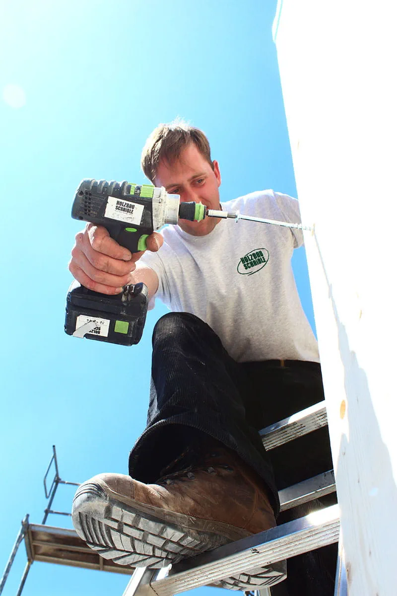 Der Akku-Bohrschrauber DRC 18/4 von Festool im Einsatz mit einem Zimmerer auf der Leiter.