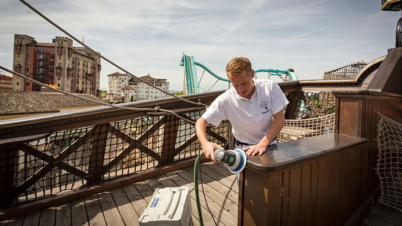 Ein Maler des Europa-Parks bearbeitet die Oberfläche mit einem Schleifer von Festool.