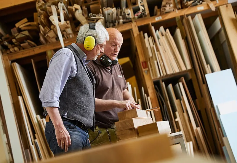 Der Tischler Schillings und sein Kunde Möllmann betrachtet die Strukturen des Holzes.