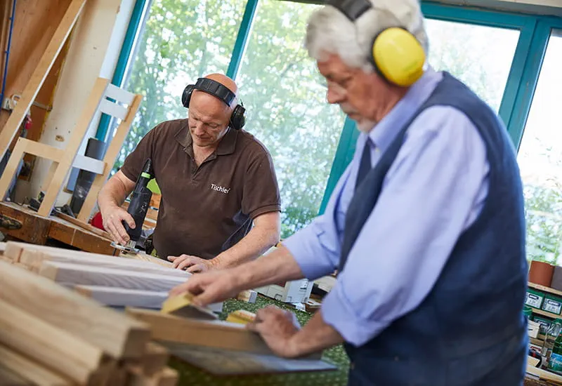 Der Tischler Schillings und Möllmann bereiten die Einzelteile des Schaukelstuhls vor.