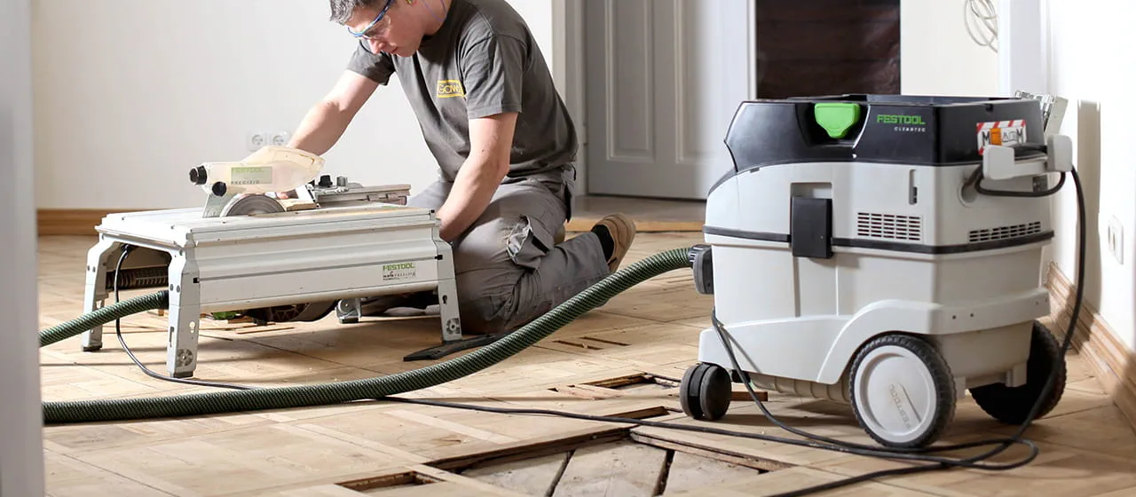 Der Blick auf die Baustelle lässt noch einige Lücken erkennen. Diese werden mit neuen Dielen gefüllt, die Jarek Gawina mit der Tischzugsäge anpasst.